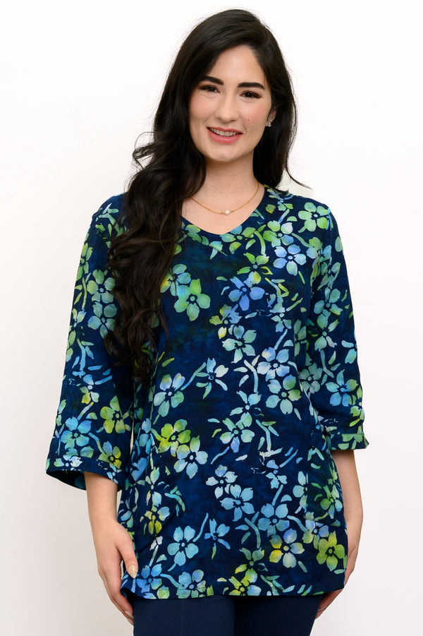 Woman wearing a blue and green floral top and navy pants against a white background, front view