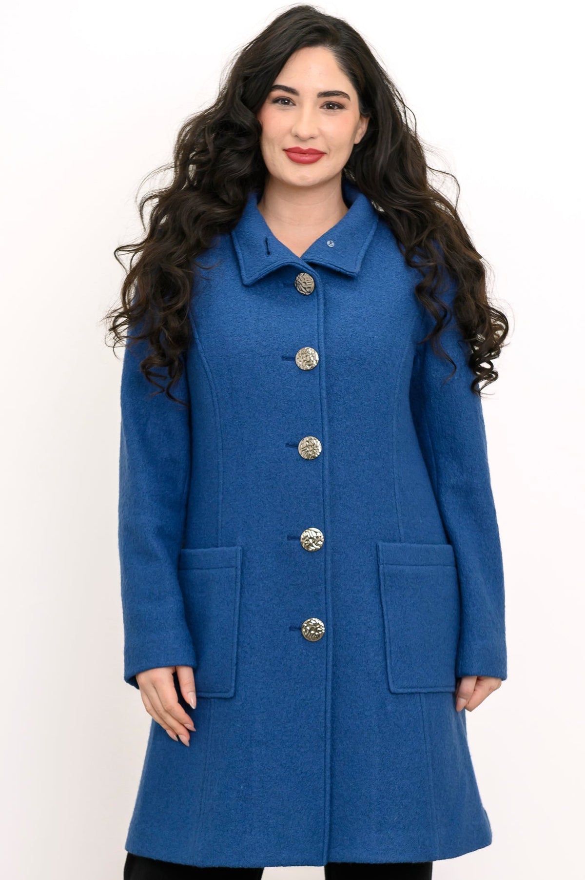 Woman wearing a blue coat with silver buttons and pockets on a white background, front view