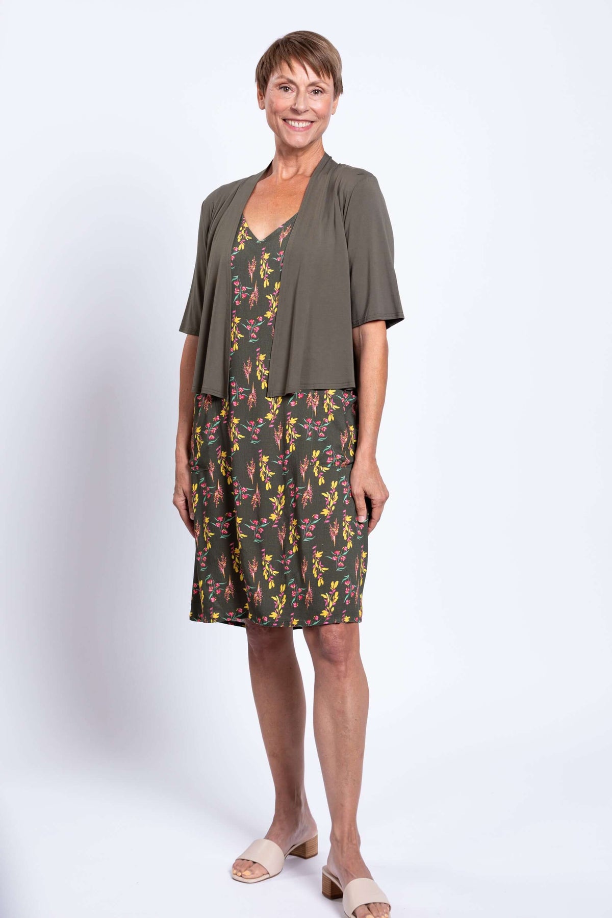 Woman wearing green floral dress with olive cardigan, front view