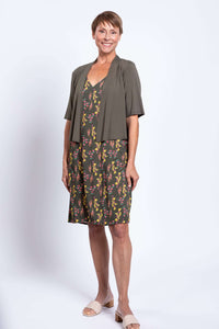 Woman wearing green floral dress with olive cardigan, front view