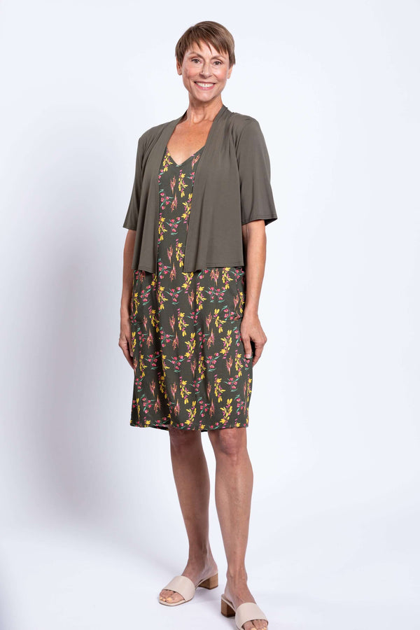Woman wearing green floral dress with olive cardigan, front view