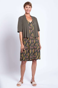 Woman in green floral dress with open olive cardigan, front view