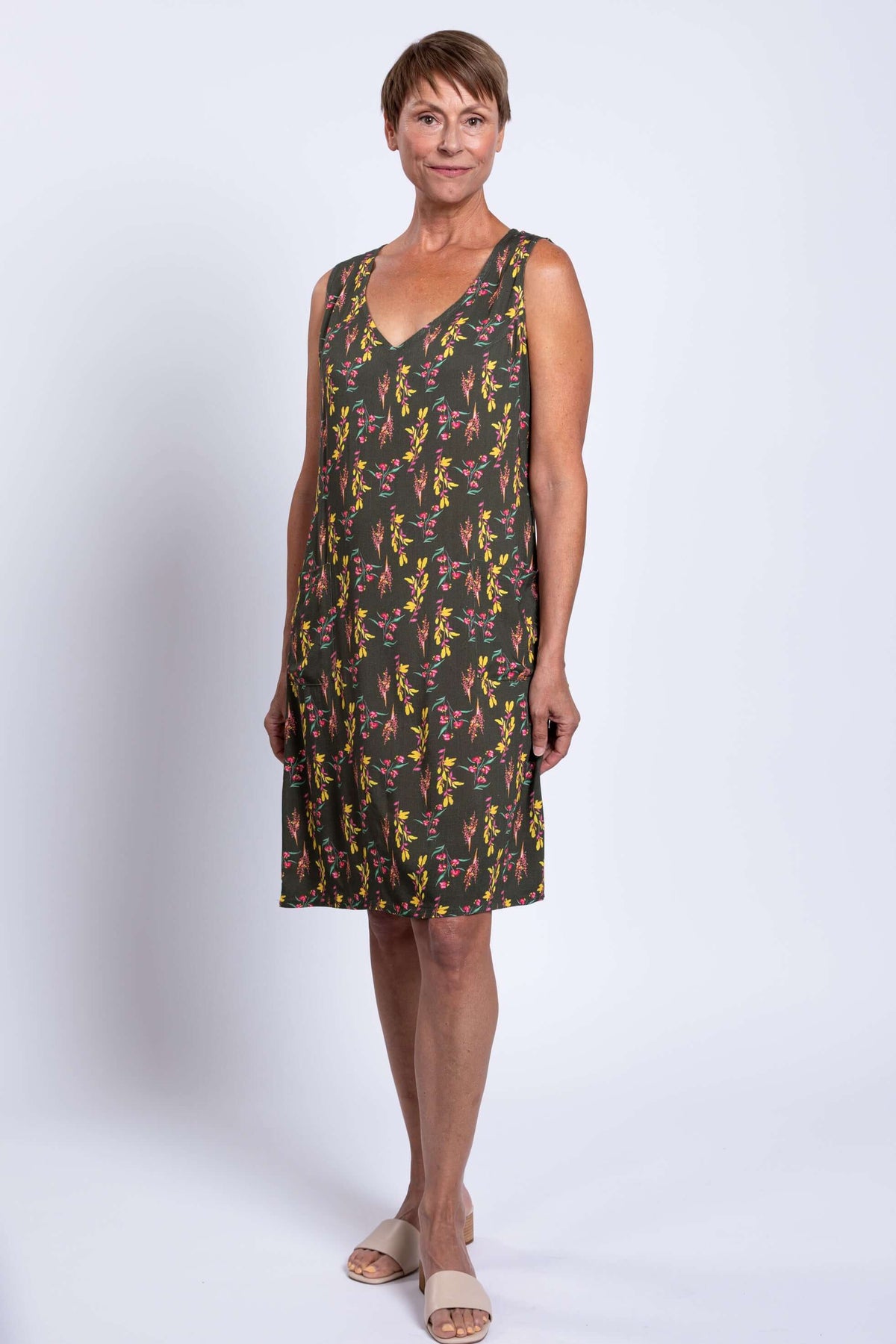 Woman wearing sleeveless green floral V-neck dress, front relaxed pose