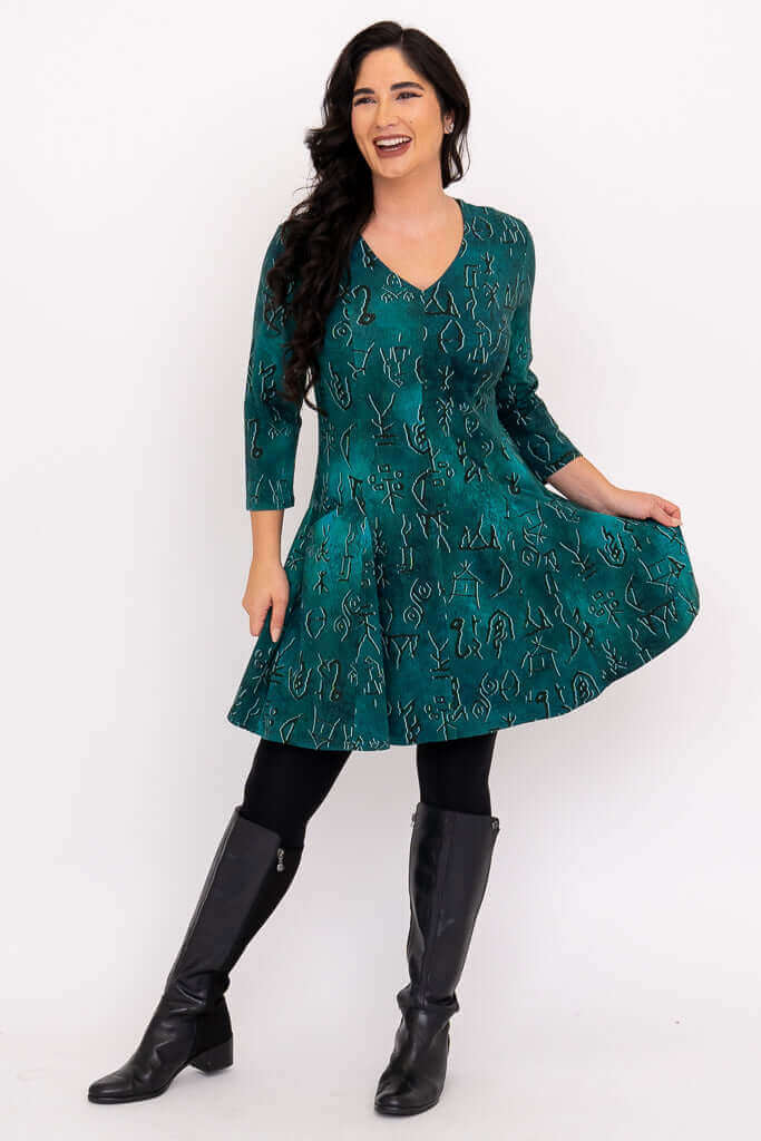 Woman smiling, showcasing the fit and flare skirt of the teal abstract Wilma Tunic dress