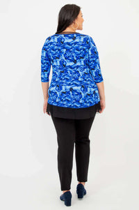 Back view of woman wearing the blue floral top with mesh underlay, showing full outfit