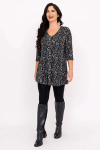 Woman walking forward in a floral A-line bamboo tunic with 3/4 sleeves and black boots