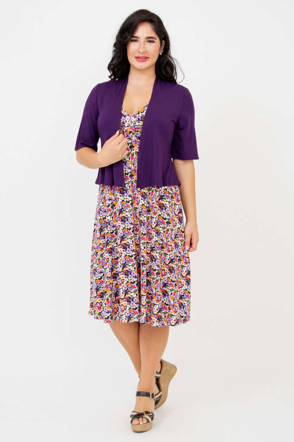 Woman in a floral fit and flare dress with a purple short-sleeve open cardigan