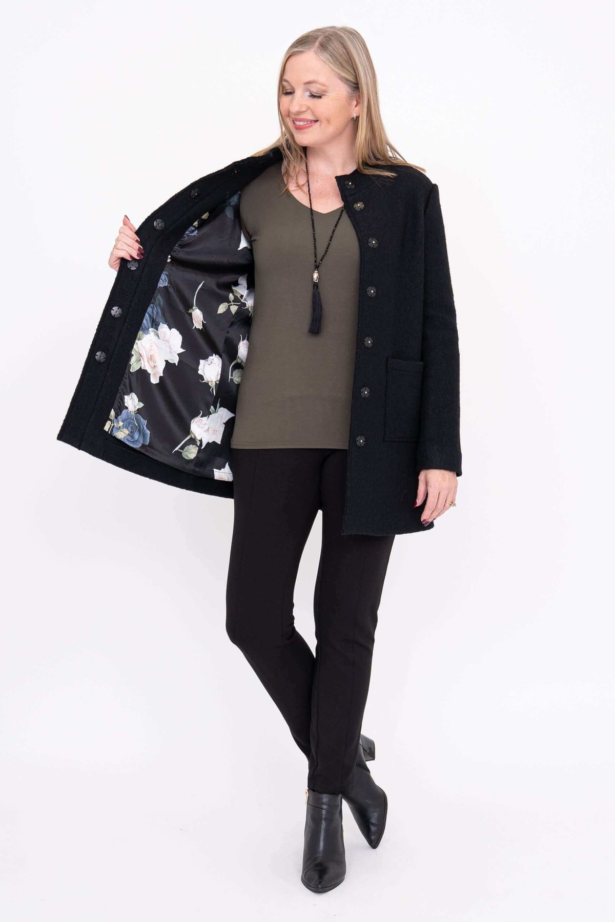 Woman displaying the floral satin lining inside the black boiled wool coat