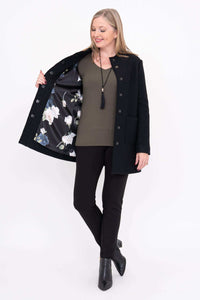 Woman displaying the floral satin lining inside the black boiled wool coat