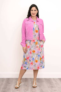 Woman in floral shift dress with pink jacket, hands in pockets