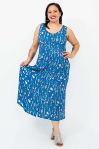 Woman holding out one side of a blue floral maxi dress, showcasing flow
