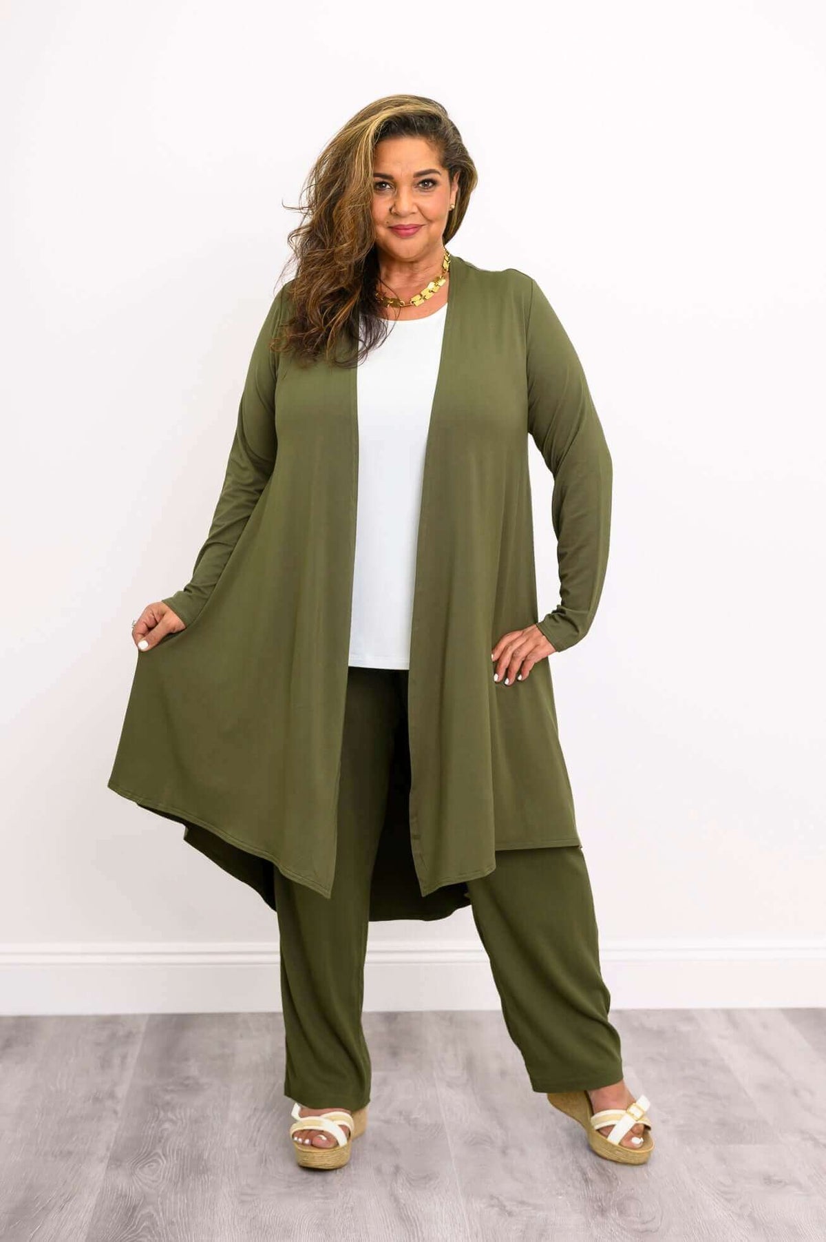 Model displaying flowy olive green open-front duster, hands holding the rounded hem