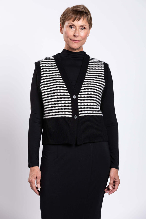 Front view of model wearing black and white striped wool-cashmere vest over black outfit