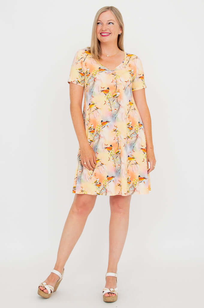 Woman smiling in flowing bird print bamboo dress, showcasing side and front