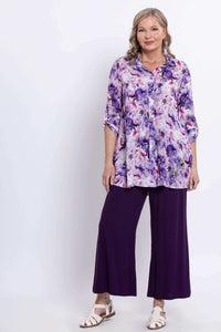 Front angled view of model wearing floral tunic and purple pants
