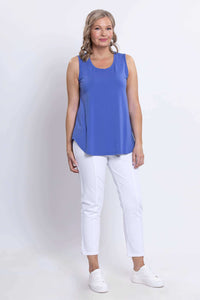 Front angled view of woman in blue tank top and white pants
