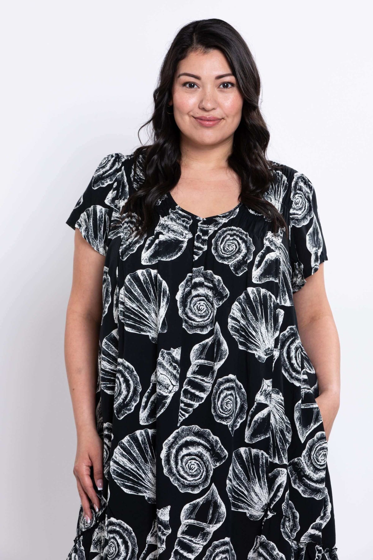 Close-up front view of a woman in the Noosa dress with shell pattern and pockets