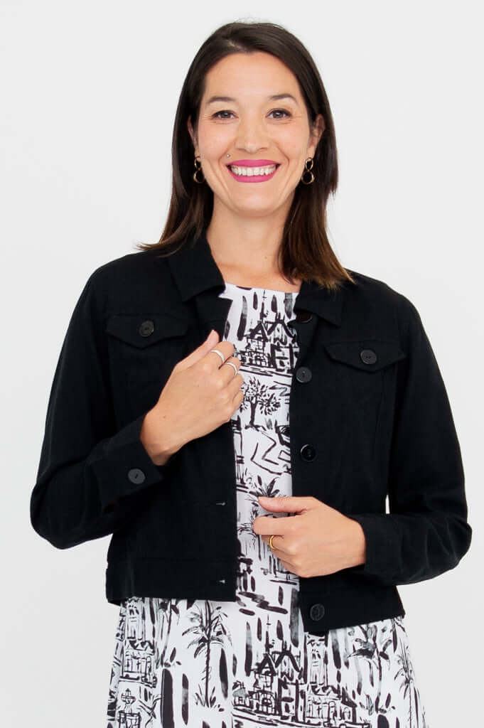 Front close-up view of model wearing a black cropped jacket over a patterned dress