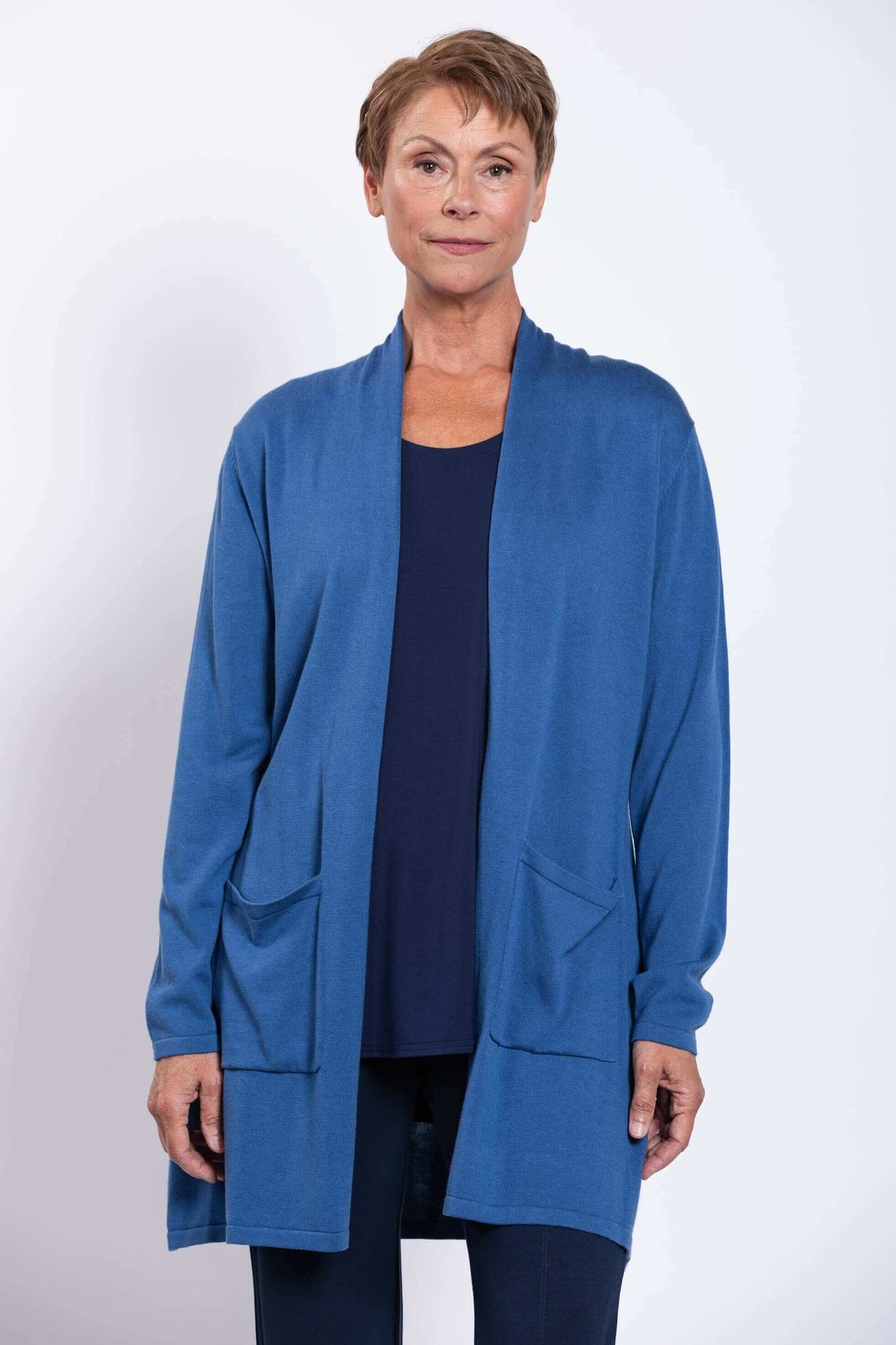 Front close-up of a woman wearing a blue open-front cardigan with patch pockets