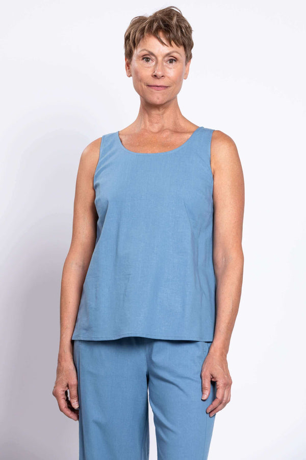 Woman wearing a sleeveless blue linen tank top with matching pants, close-up front view