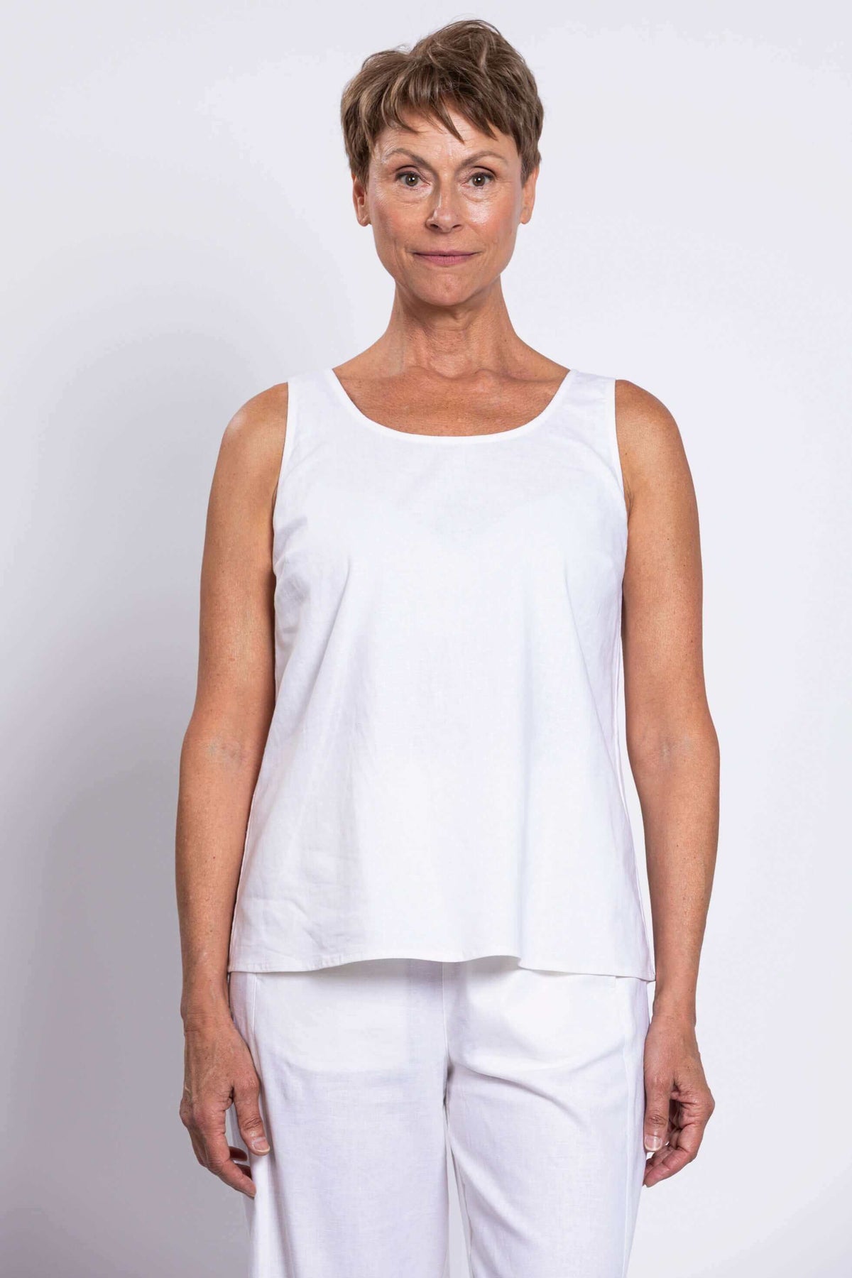 Front close-up view of woman wearing a sleeveless white linen tank top