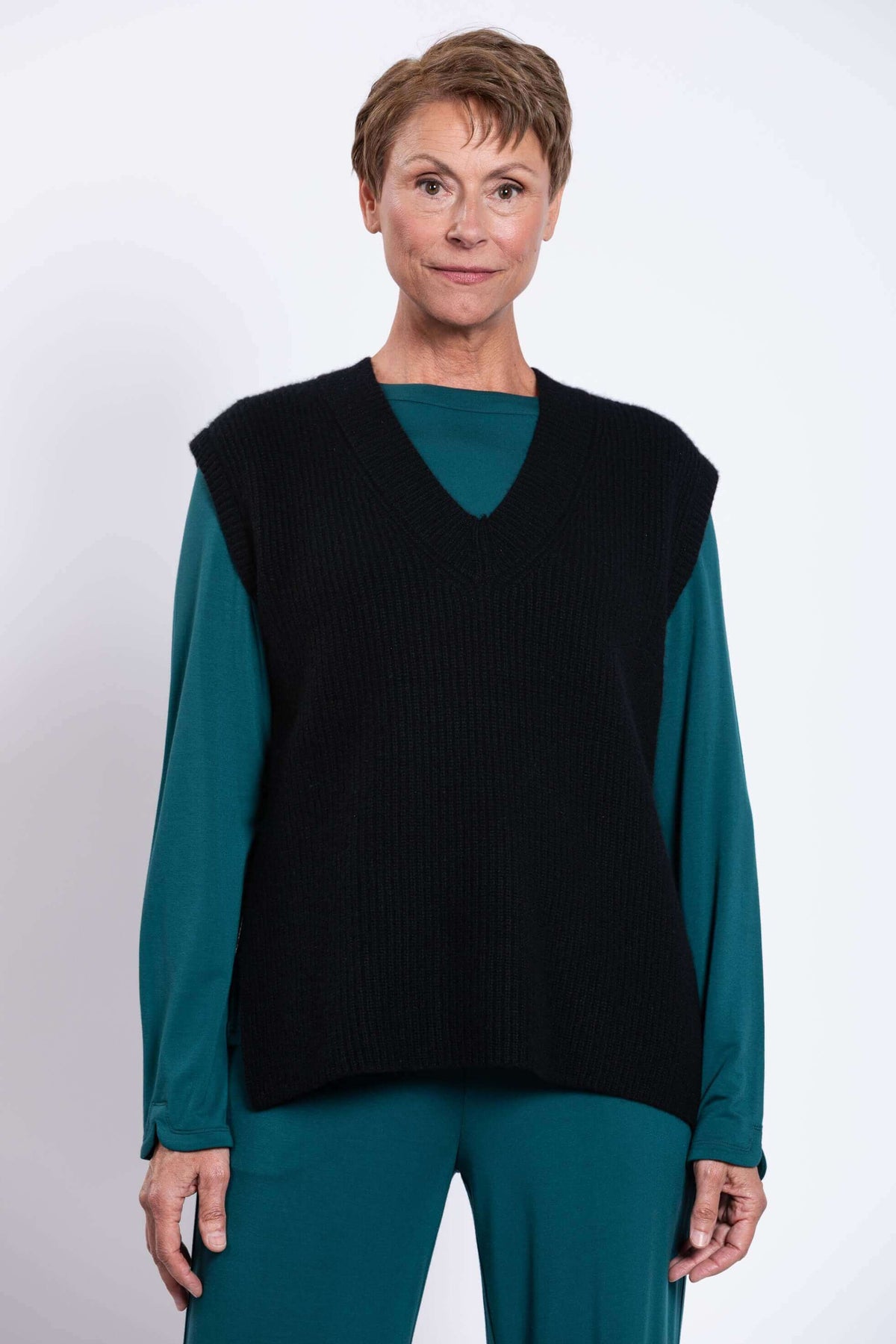 Front closeup view of woman wearing black wool-cashmere vest over teal top