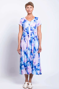 Woman standing facing forward in a blue and purple watercolor print button-up dress