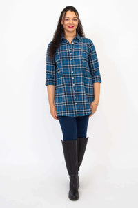 Front view of woman in blue plaid button-up tunic and knee-high boots