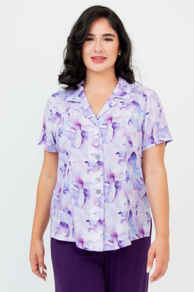 Front view of woman wearing a purple watercolor button-up short sleeve shirt