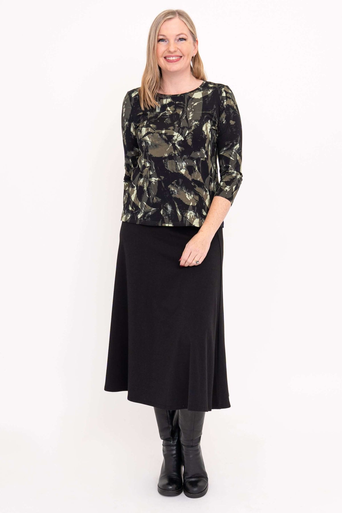 Woman in olive brush print tee and long black skirt, facing forward