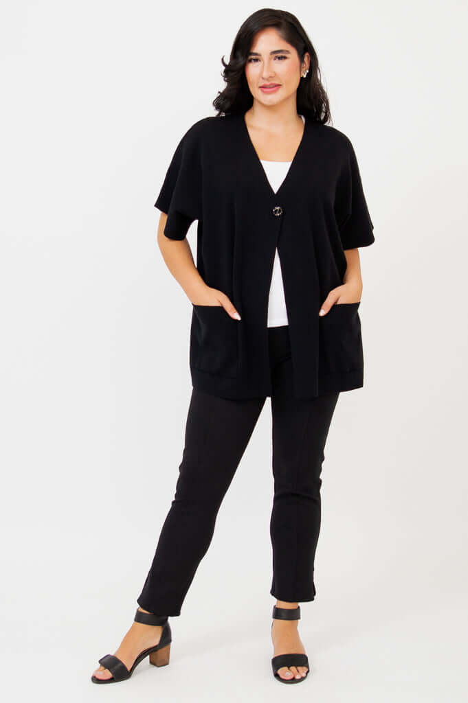 Woman showing front with hands in pockets wearing a black cotton cardigan and black pants