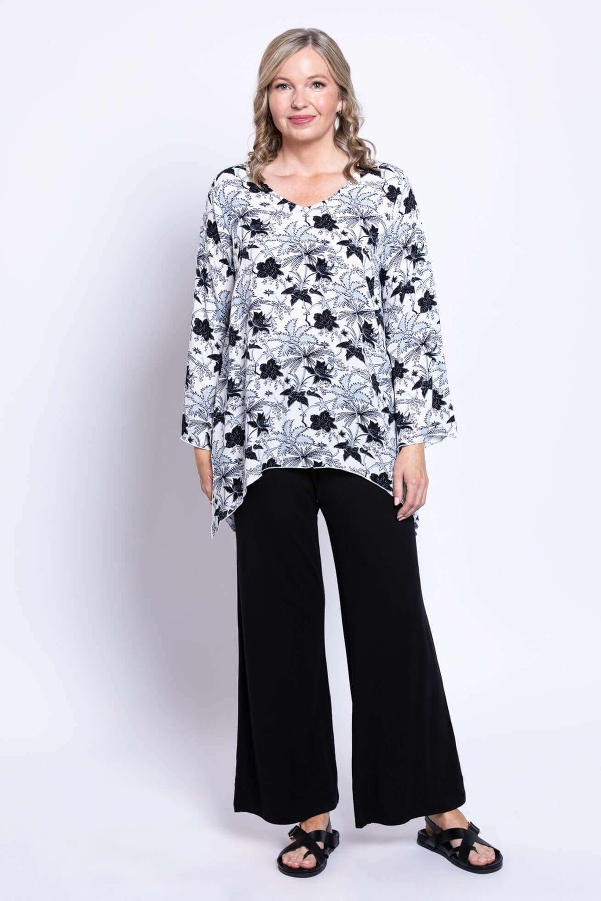 Full front pose of woman wearing bohemian shark-bite hem top with bell sleeves