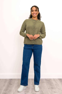 Woman wearing olive green cable knit cashmere cardigan and blue jeans, hands clasped, front view