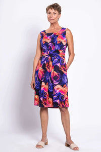 Woman posing in a bright swirl print sleeveless dress, hands in pockets