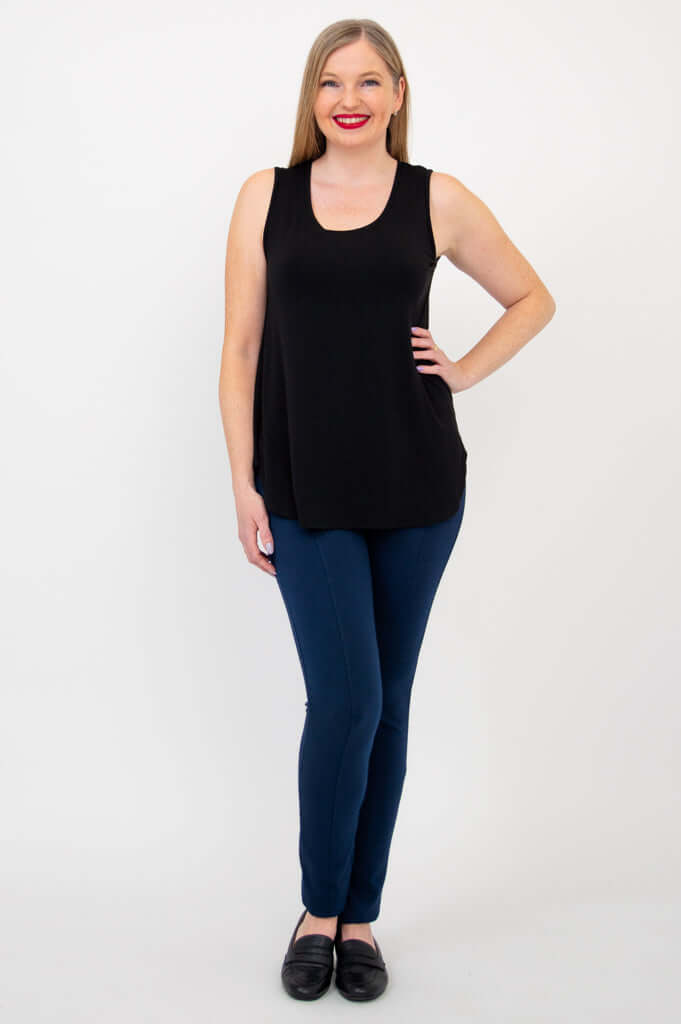 Woman standing with hand on hip, wearing black tank top and blue pants