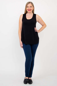 Woman standing with hand on hip, wearing black tank top and blue pants