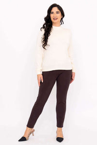 Front standing view of woman in ivory sweater with wavy hair and brown pants