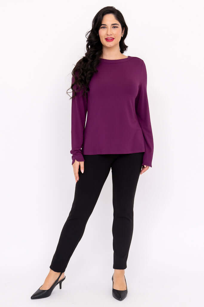 Front view of woman in a purple boat neck top and black pants