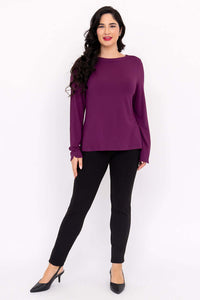 Front view of woman in a purple boat neck top and black pants