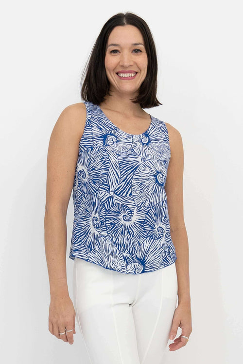 Woman wearing sleeveless blue and white shell print tank top, front view