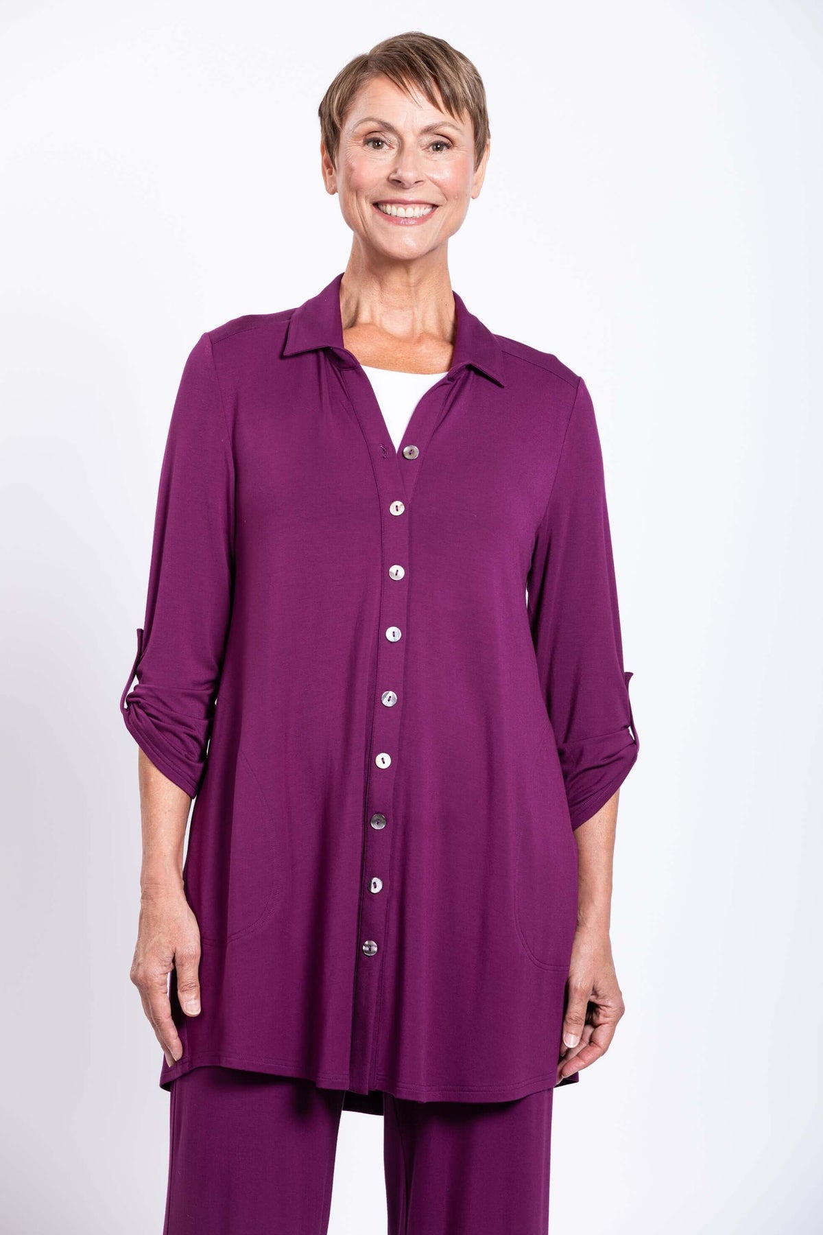 Front view of a model wearing a long plum button-down bamboo tunic with rolled sleeves