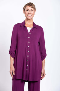 Front view of a model wearing a long plum button-down bamboo tunic with rolled sleeves