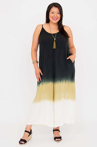 Front view of a woman wearing a black, olive, and ivory ombre jumpsuit with adjustable straps