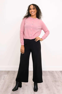 Full body front view of woman modeling pink cardigan, hand on hip