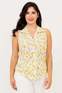 Front view of model wearing sleeveless yellow floral shirt and white pants