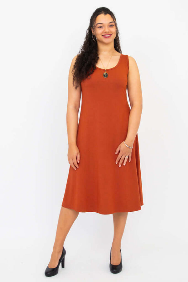 Front view of a woman wearing the Becca dress in burnt orange with scoop neckline