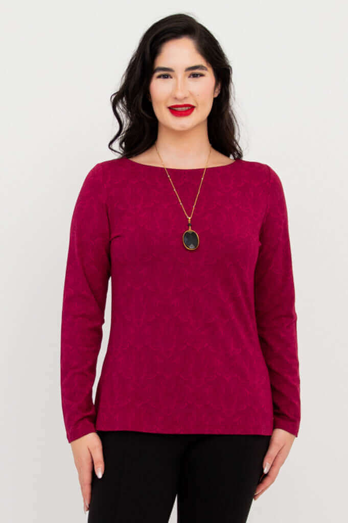 Woman wearing a berry long sleeve top and black pants, facing forward