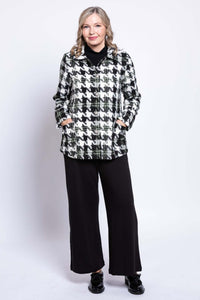 Front view of woman wearing a black and white houndstooth coat with hands in pockets