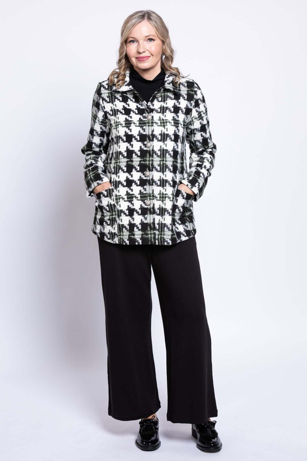 Front view of woman wearing a black and white houndstooth coat with hands in pockets