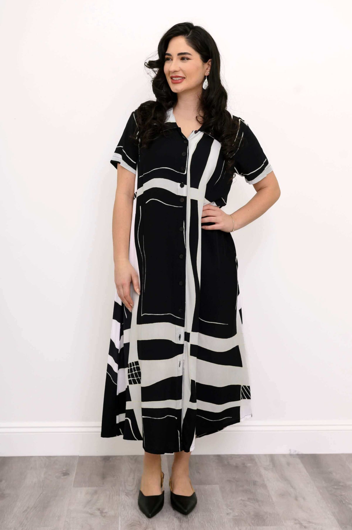 Front view of woman wearing black and white geometric A-line button-up midi dress